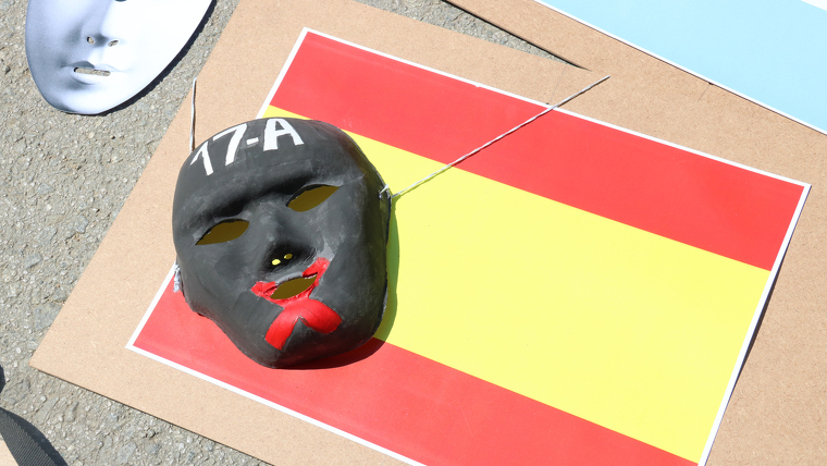 Els manifestants han col·locat una màscara negra amb una creu veremella sobre la bandera espanyola
