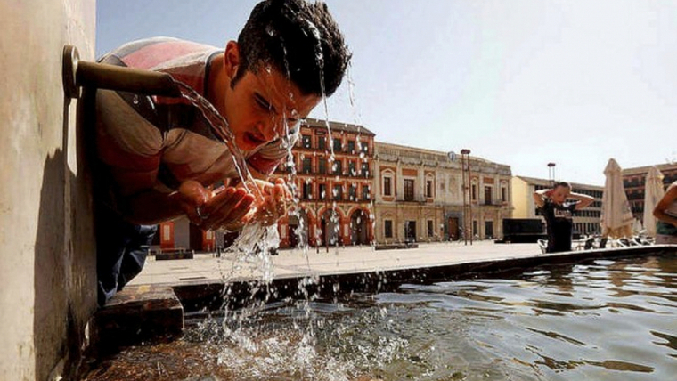 Un jove es refresca en una font sota un sol de justÃ­cia i temperatures extremes
