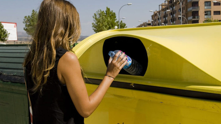 Una mujer deposita una botella de plástico en un contenedor amarillo. / Ecoembes
