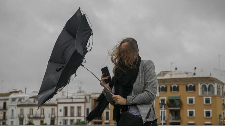 Imatge d'una dona amb el paraigÃ¼es trencat a causa de les fortes ventades