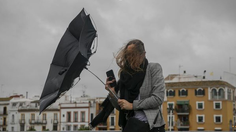 Imatge d'una dona amb el paraigües trencat a causa de les fortes ventades