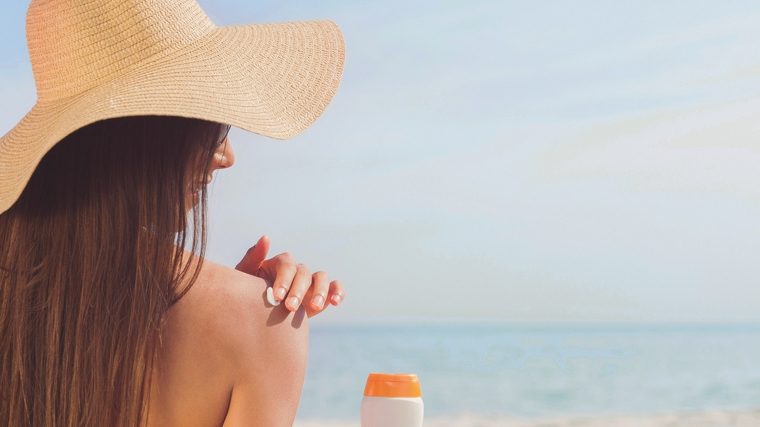 Una dona posant-se crema solar en una platja