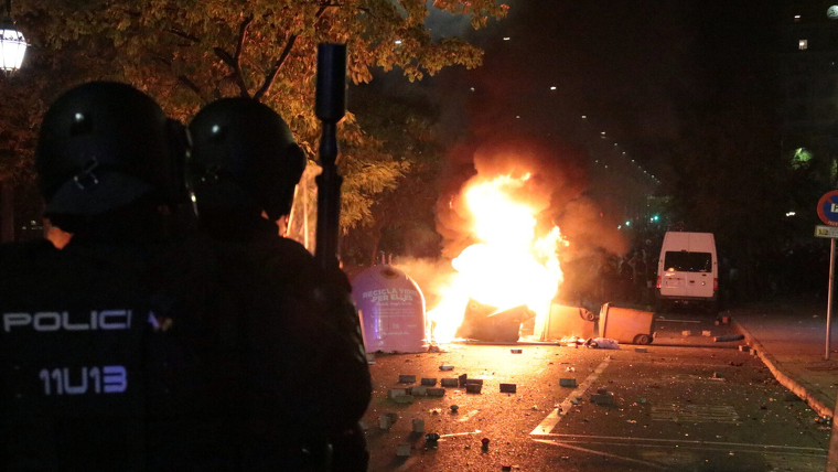 Antiavalots de la policia espanyola observant contenidors encesos i els manifestants