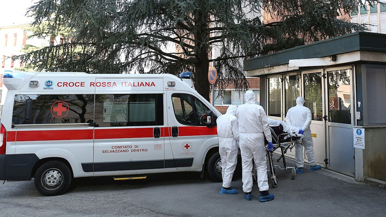 Una ambulancia de la Cruz Roja italiana con sanitarios con trajes de protecciÃ³n contra epidemias