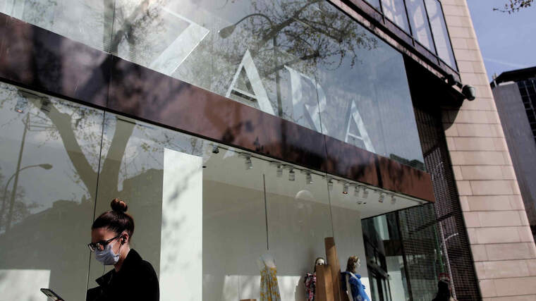 Una dona amb mascareta passant per davant d'una tenda de Zara de Madrid