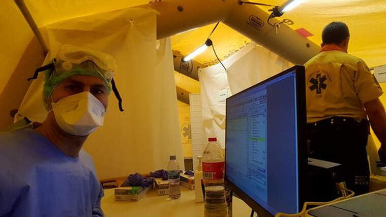 L'infermer Xavi MÃ¡rquez davant del seu ordinador amb mascareta i equip de protecciÃ³ el 24 de marÃ§ de 2020