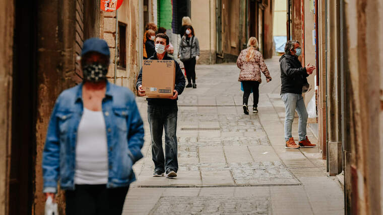 Gent caminant pel carrer amb mascaretes.