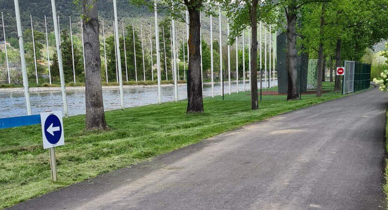 Pla obert on es veu una senyal que indica el sentit de la circulació al camí que envolta part del canal d'aigües tranquil·les del Parc del Segre