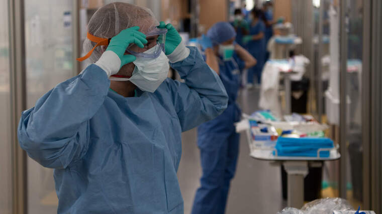 Un professional sanitari es protegeix abans d'entrar en contacte amb pacients a l'Hospital ClÃ­nic de Barcelona