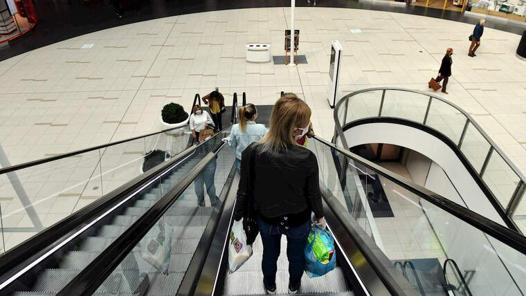 Imatge d'una dona baixant per una escala mecÃ nica en un centre comercial