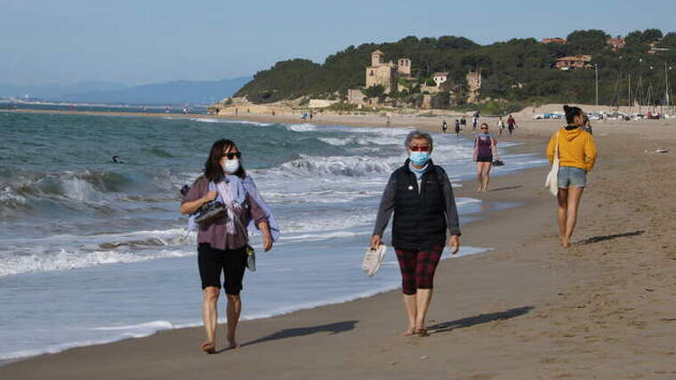Pla general de dues dones amb mascareta caminant per la platja d'Altafulla en el primer dia permÃ¨s per sortir a practicar esport.