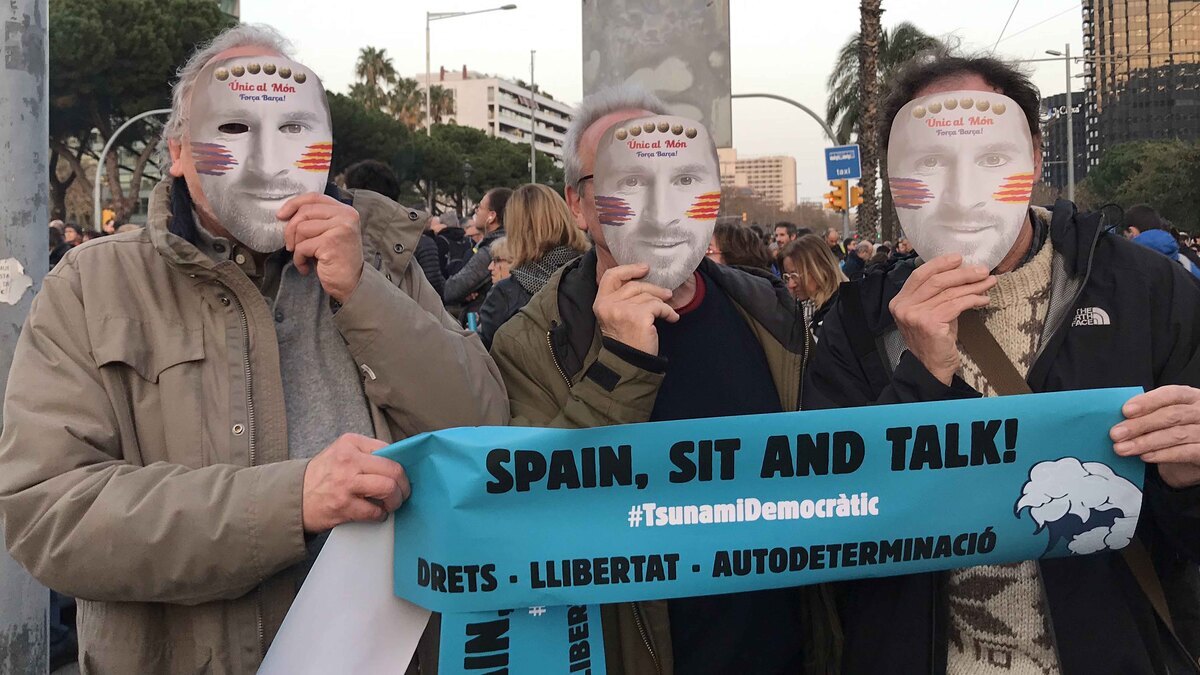 Tres homes amb la careta que han repartit independentistes abans del Clàssic del 18 de desembre de 2019