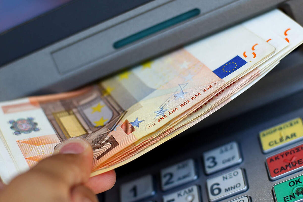 Primer pla d'una mà traient bitllets de 50 euros d'un caixer automàtic