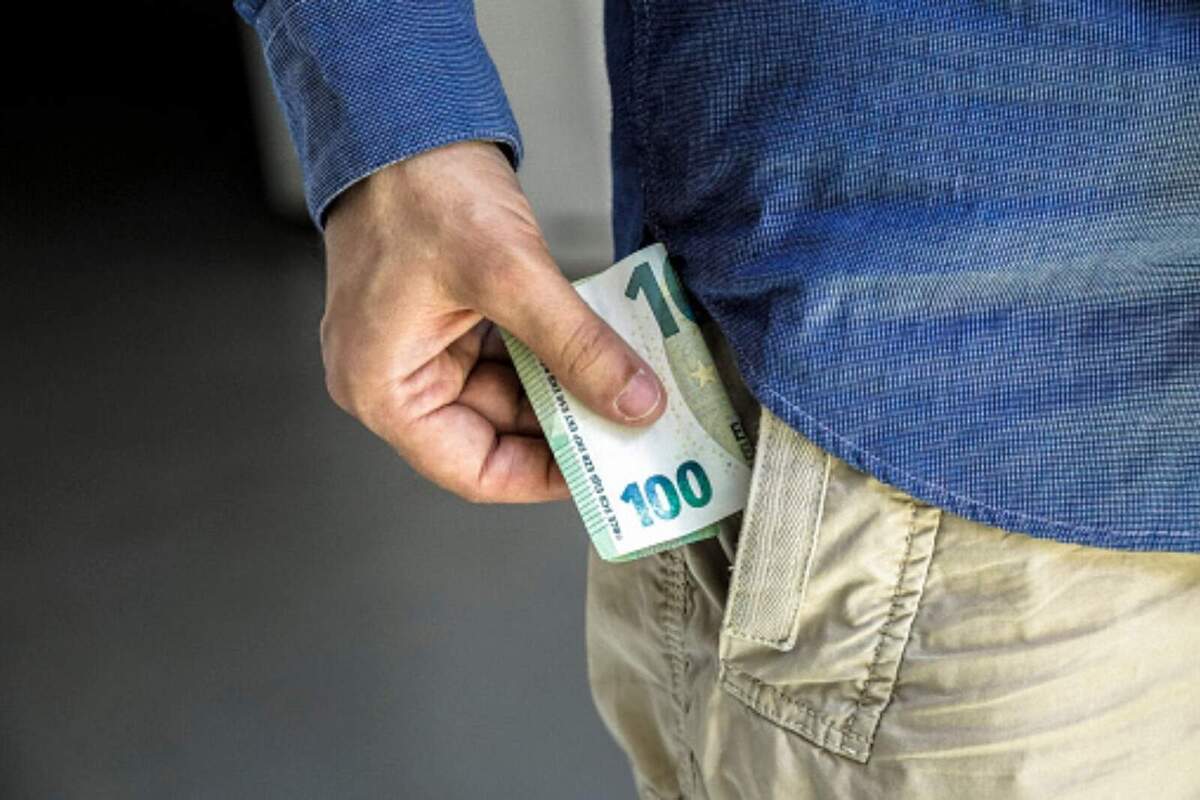 Detall d'una persona guardant-se un bitllet de 100 euros a la butxaca