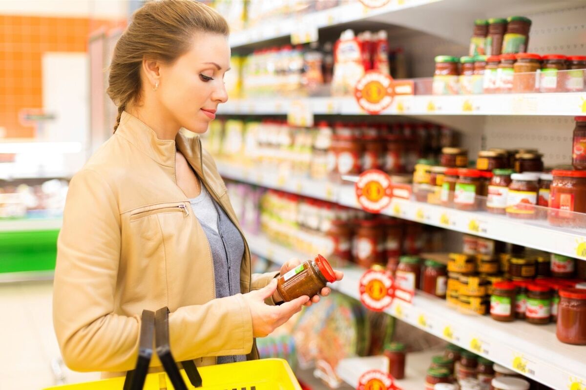 Imatge d'una noia comprant a un supermercat amb un producte a les mans.