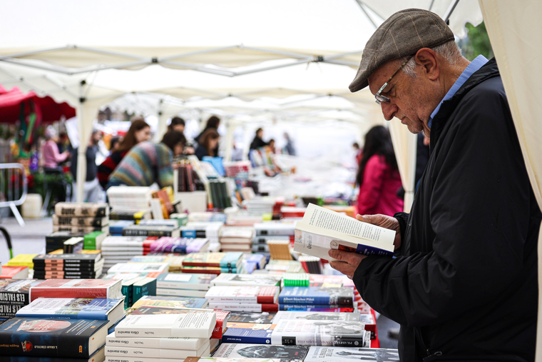 Un home fulleja un llibre en una parada al Passeig de Gràcia de Barcelona