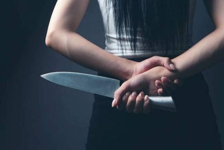 Foto d'una dona amb un ganivet amagat a l'esquena.