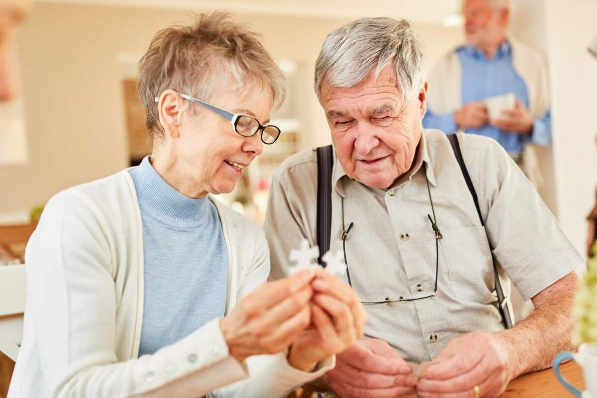 Foto de dues persones grans agafant peces d'un puzzle.