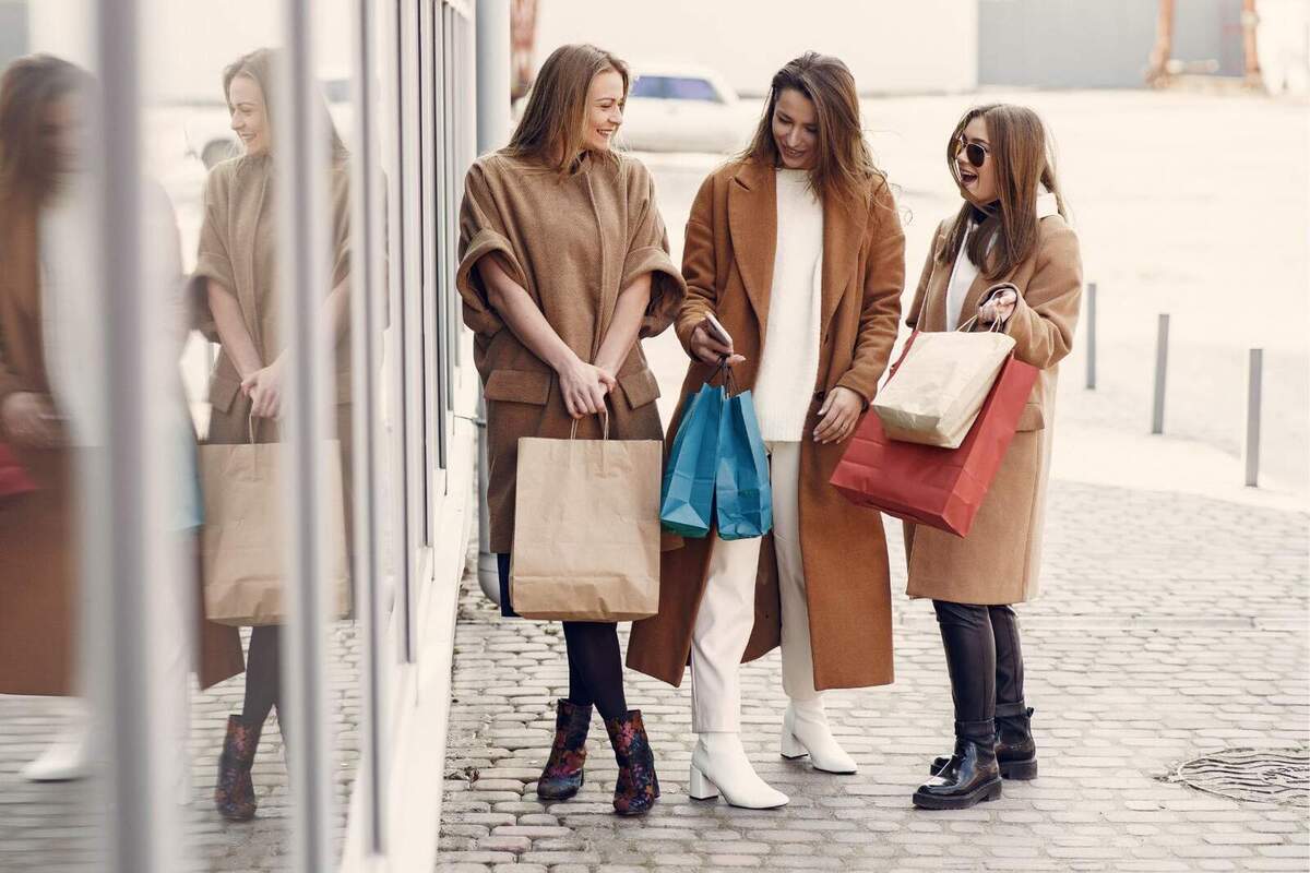 Imatge de tres dones ben abrigades fora d'un centre comercial i anant de compres