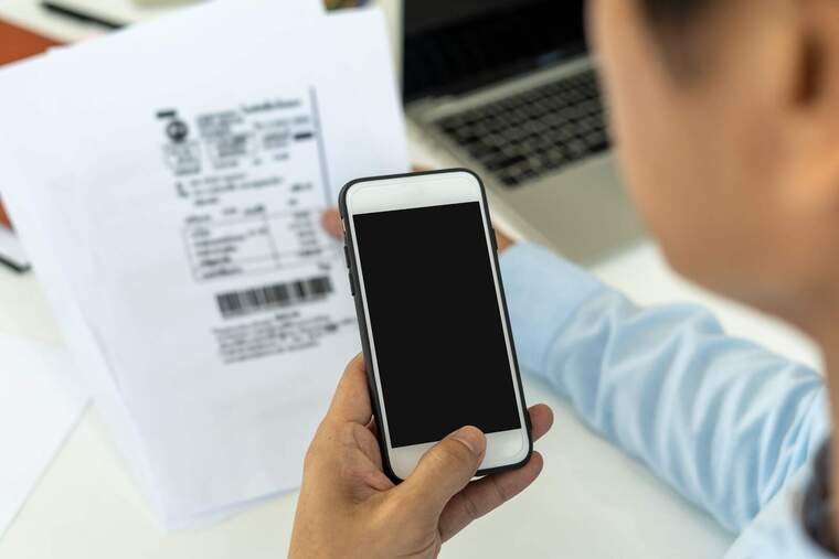 Imatge d'una persona amb un telèfon mòvil calculant el preu d'una factura