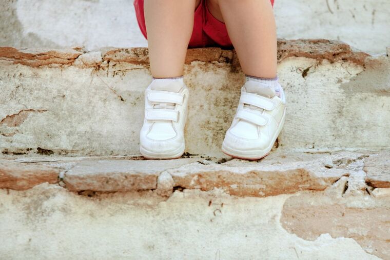 Imatge d'uns peus d'un nen assegut a unes escales de pedra
