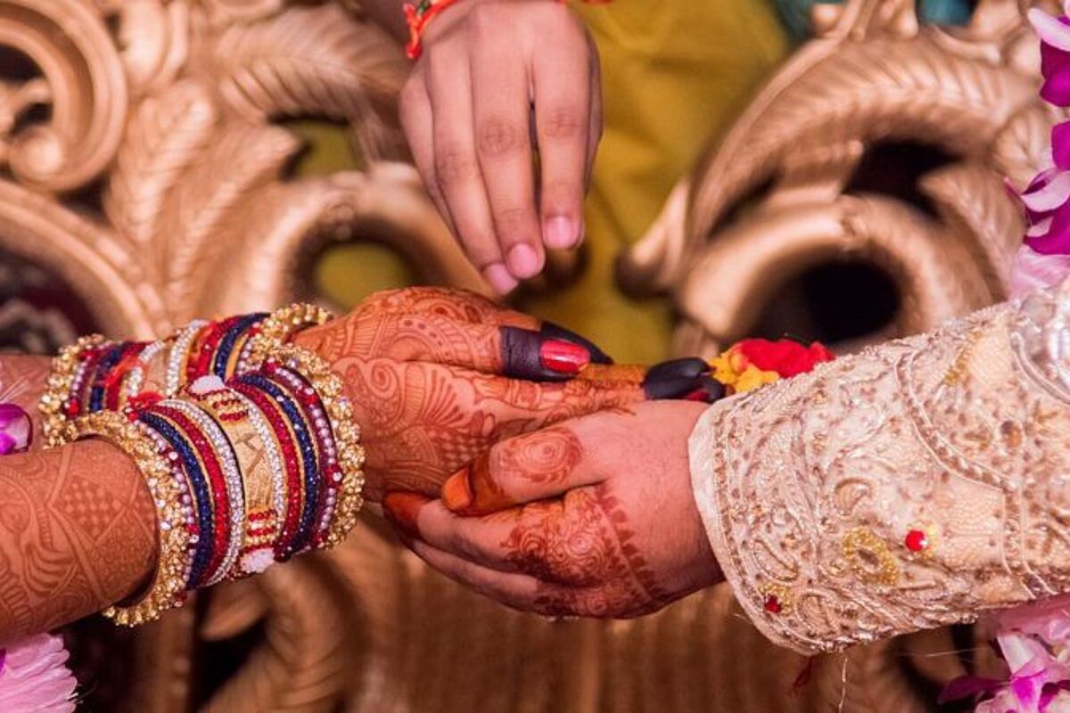 Plano detalle de las manos de una pareja india entrelazadas durante la ceremonia de su boda