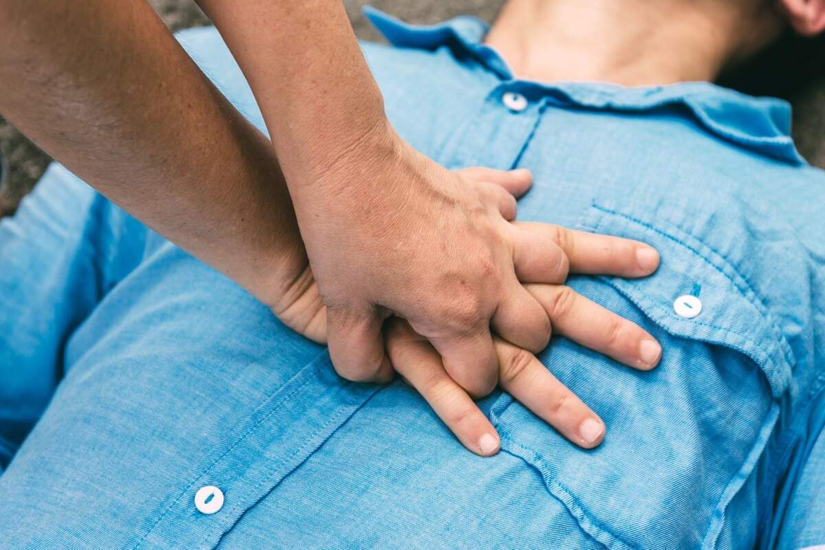 Unas manos realizando la reanimación cardiopulmonar (RCP) sobre una persona tumbada en el suelo