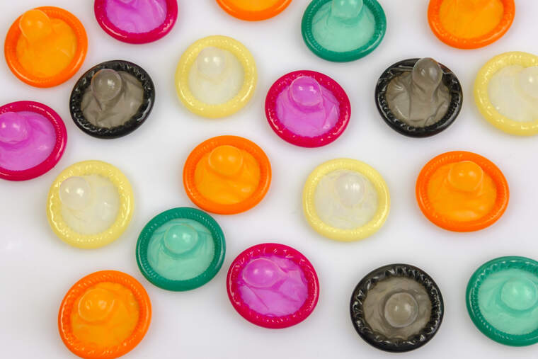 Condones de todos los colores colocados sobre una superficie blanca
