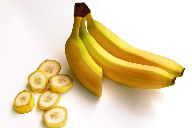 Una banana cortada parcialmente en pedazos con otras dos enteras