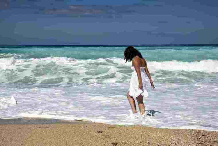 Dona passejant en una platja amb onatge