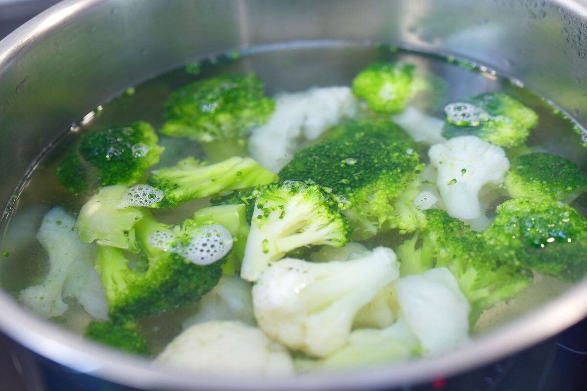Trozos de brócoli y coliflor en una olla llena de agua hervida