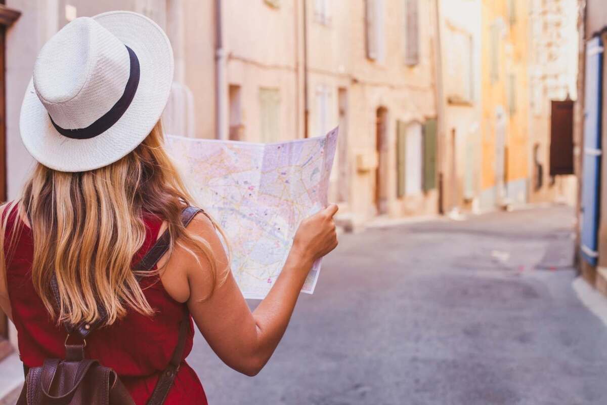 Woman with a hat looking at a map in the middle of a street without people