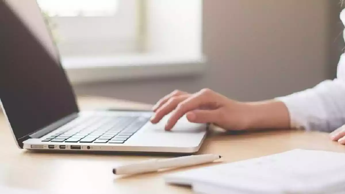 Mujer utilizando su portátil desde su mesa de escritorio Mujer utilizando su portátil desde su mesa de escritorio