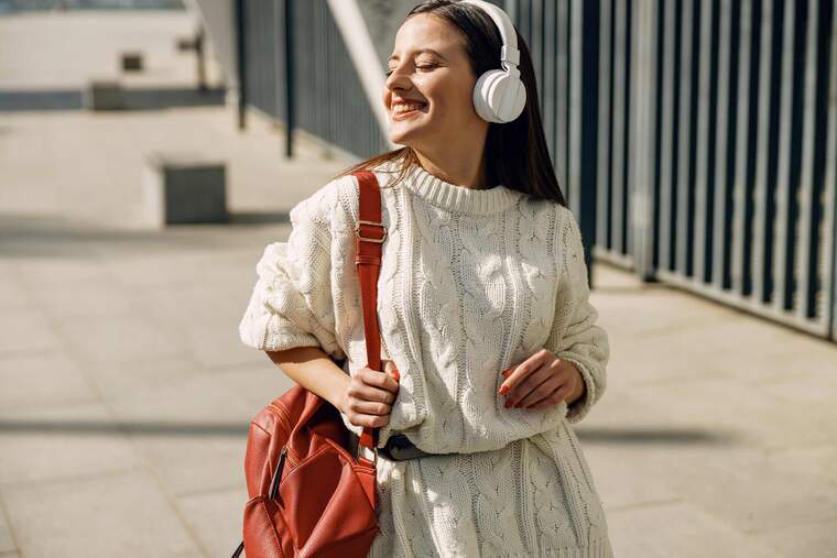 Happy woman with headphones waling down the street