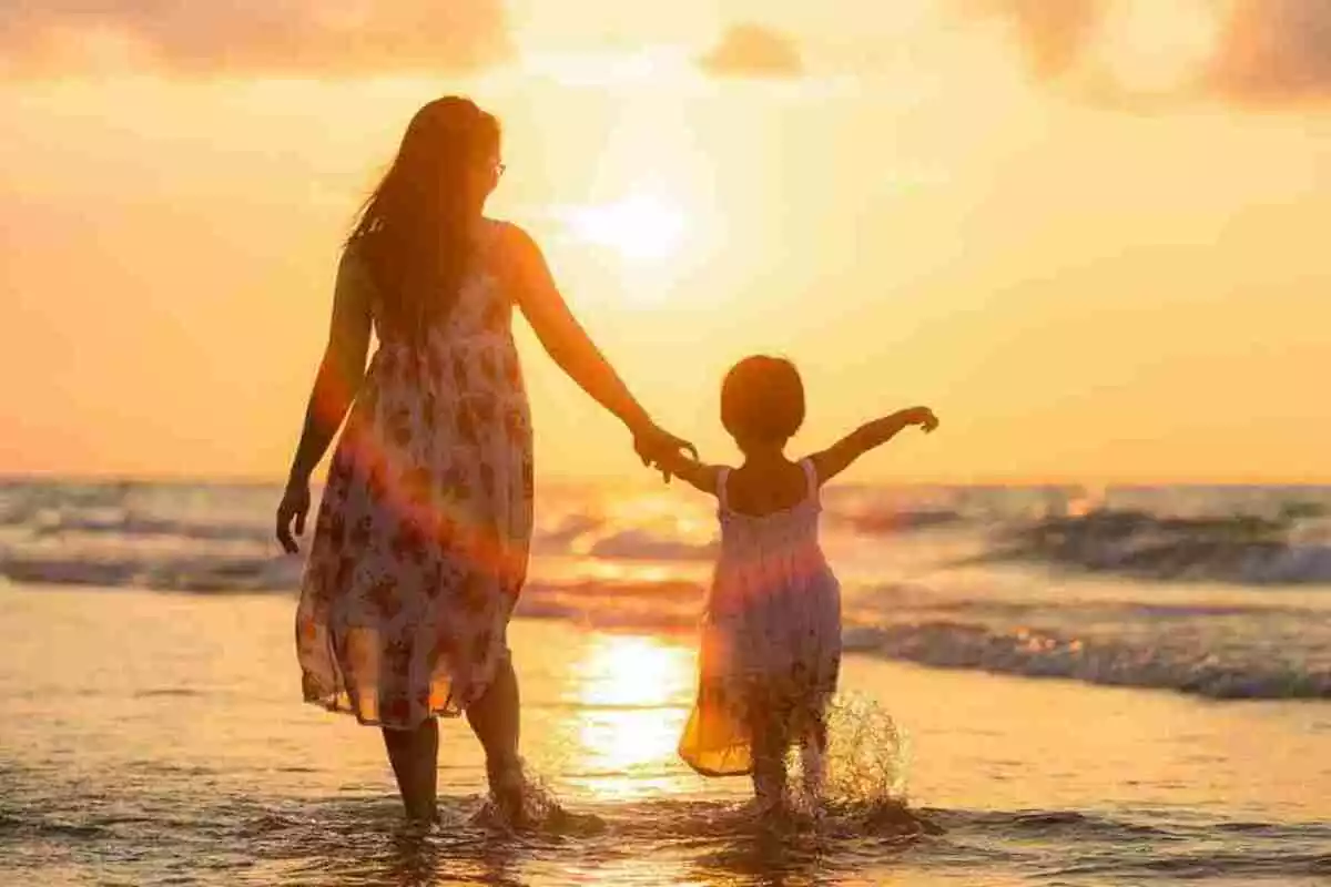 Madre con su hija caminando por la orilla del mar Madre con su hija caminando por la orilla del mar