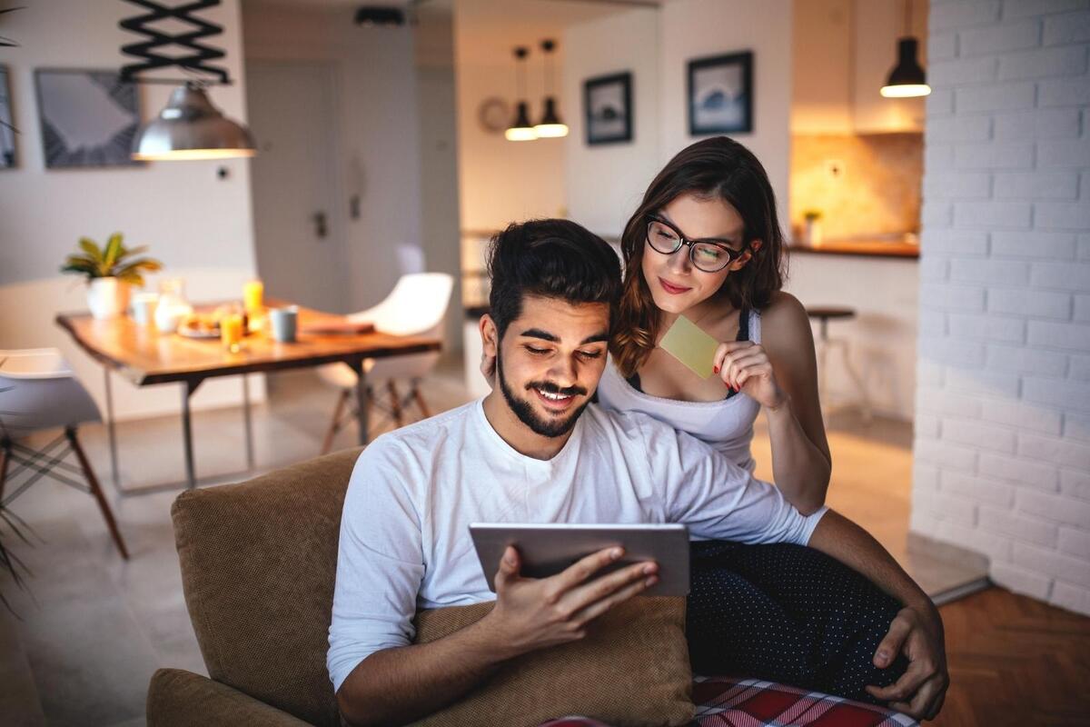 Pareja frente a tablet con tarjeta de crédito comprando