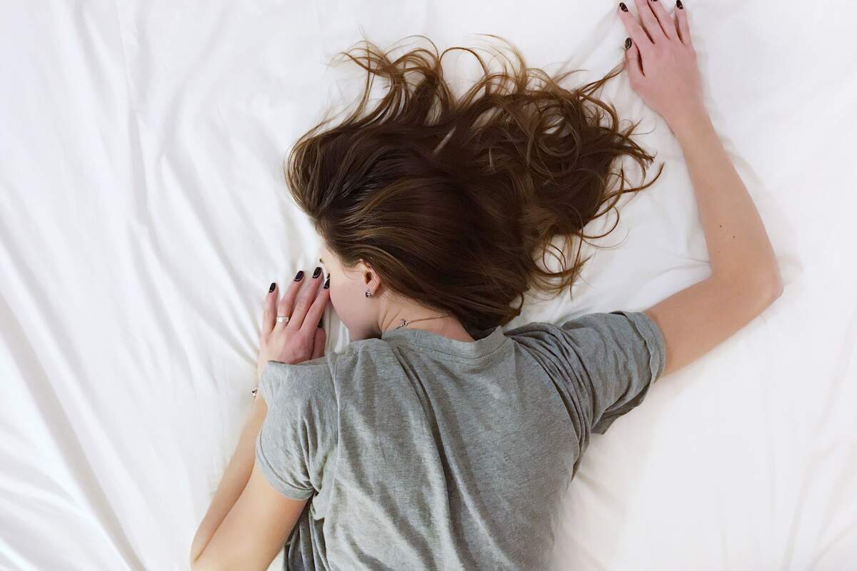 Una chica encima de una sábana blanca durmiendo