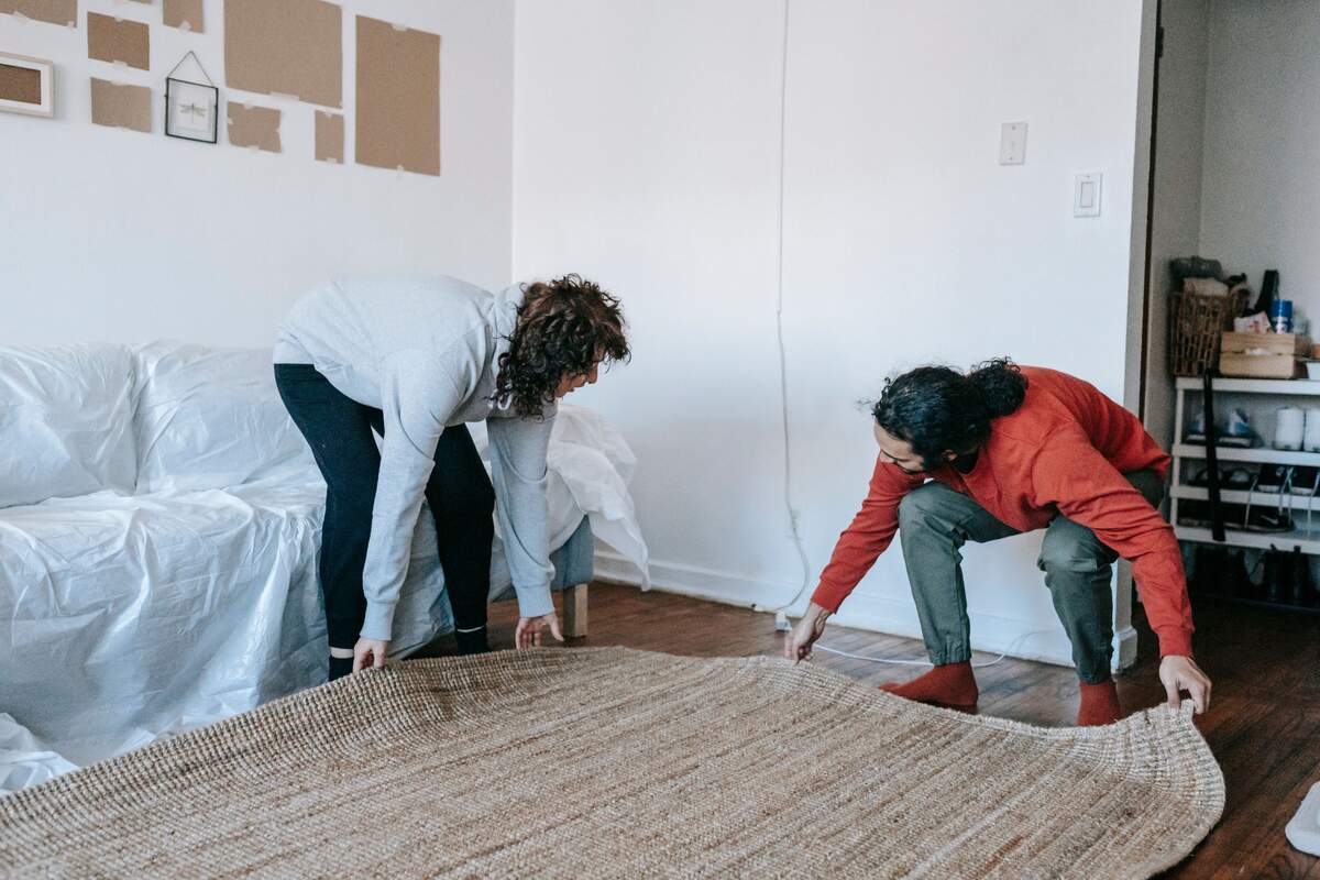Una pareja moviendo una alfombra en su piso
