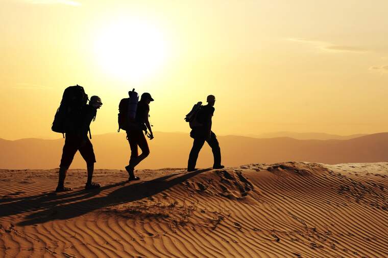 Tres personas caminando por el desierto