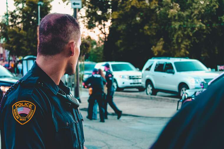 Un policía de espaldas viendo como arrestan a una persona