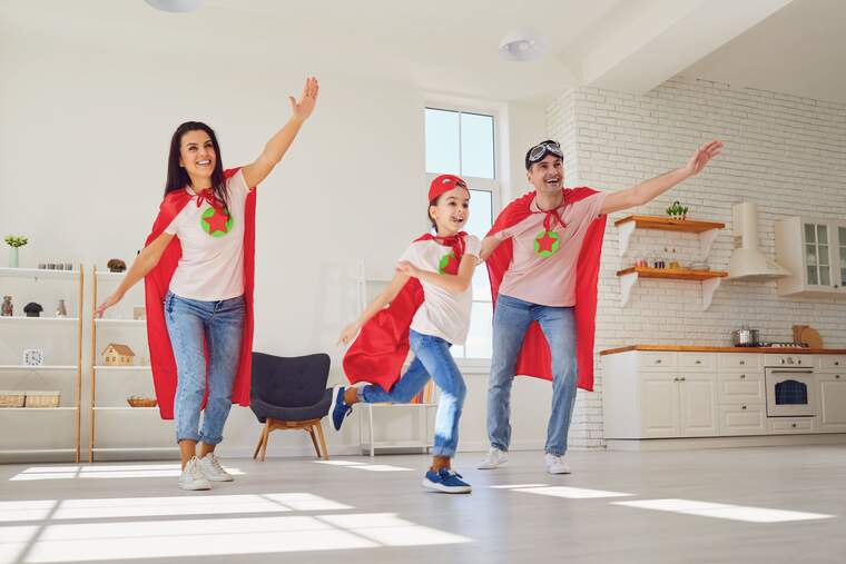 Una familia entera vestida de superhéroe en el comedor de su casa