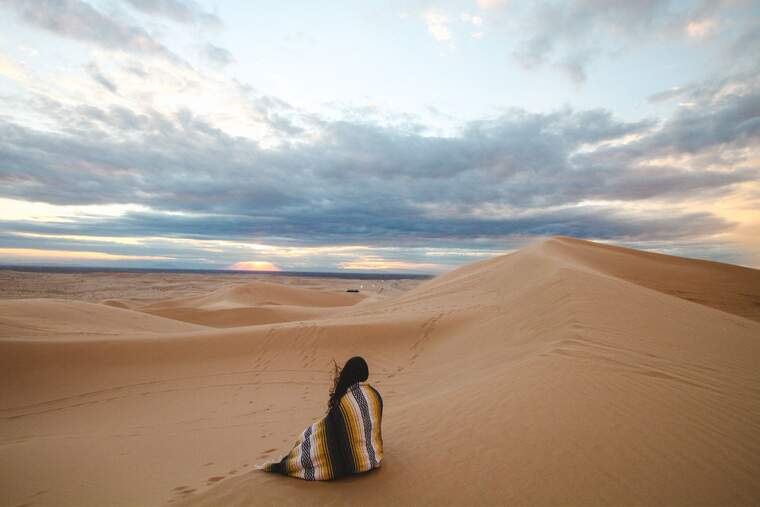 Una mujer sentada sola en las dunas del desierto