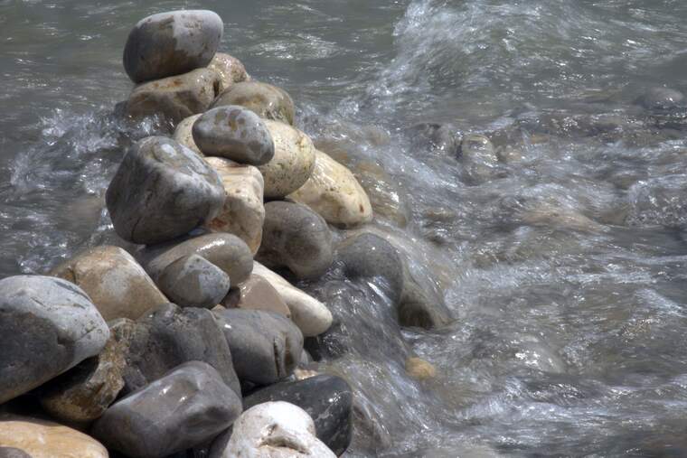 Una muralla de piedras siendo un obstáculo en el río