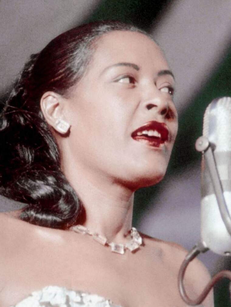 Billie Holiday cantando con el pelo arreglado y un micrófono delante