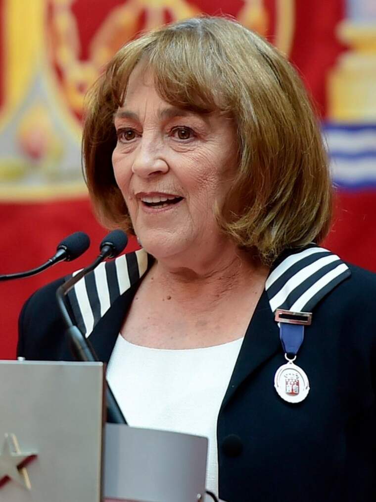 Carmen Maura hablando ante el micrófono con una medalla colgada