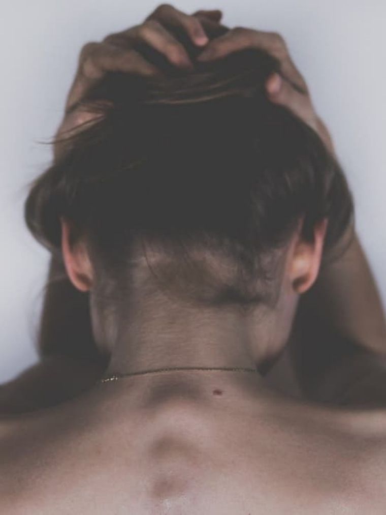 Imagen de una chica de espaldas recogiéndose el cabello