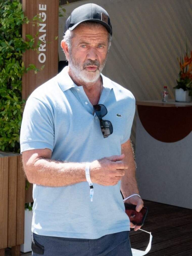 Mel Gibson con gafas de sol colgadas mientras camina por la calle