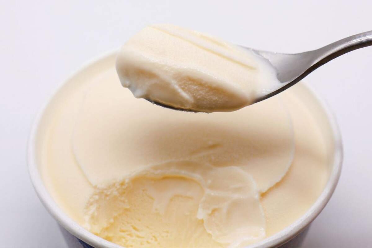 Cuchara con helado de vainilla en una tarrina