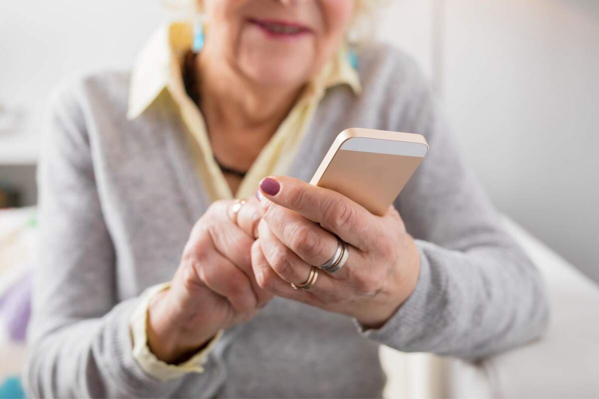 Una mujer mayor sujetando su iPhone en la mano