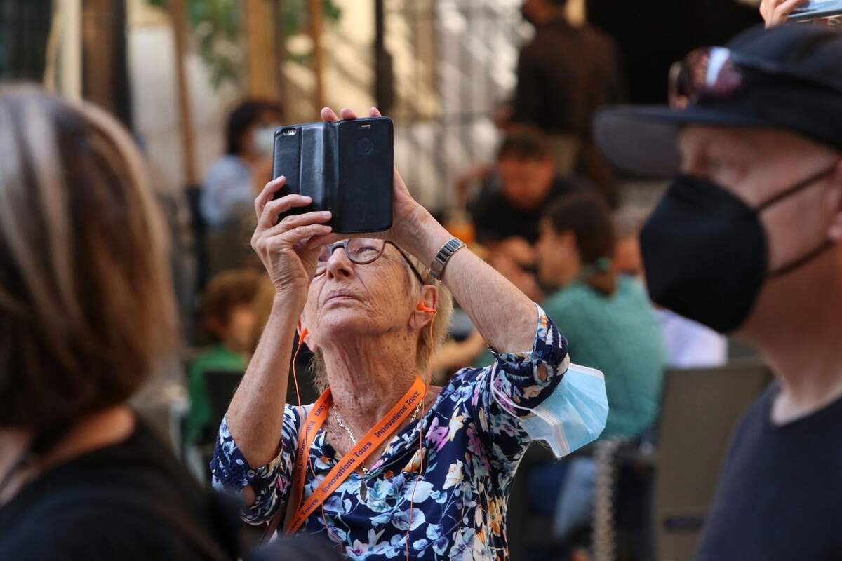 A retired woman taking photos with her mobile phone